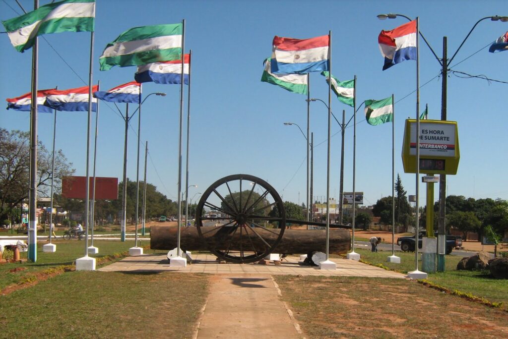 Monumento de un cañón rodeado de banderas de Paraguay y del Departamento