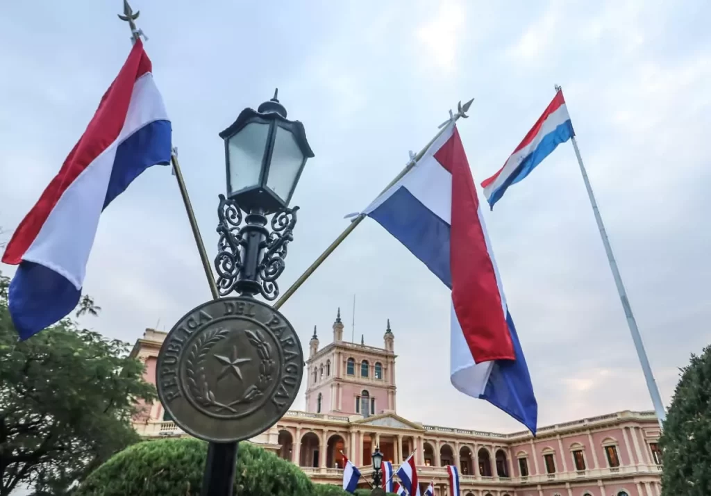 Banderas paraguayas colgadas de un faro con el Palacio López de fondo